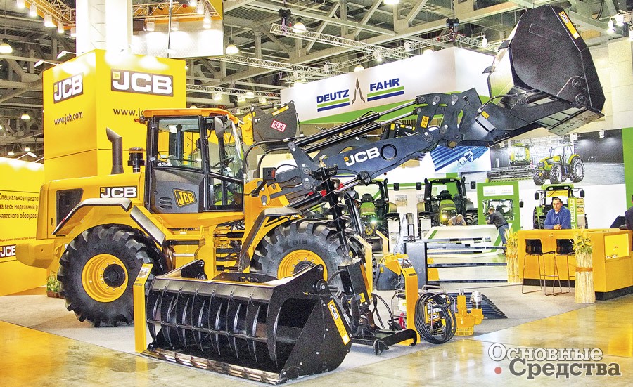 Фронтальный погрузчик JCB с двухчелюстным ковшом. Перед ним сменные сельскохозяйственный ковш и гидробур