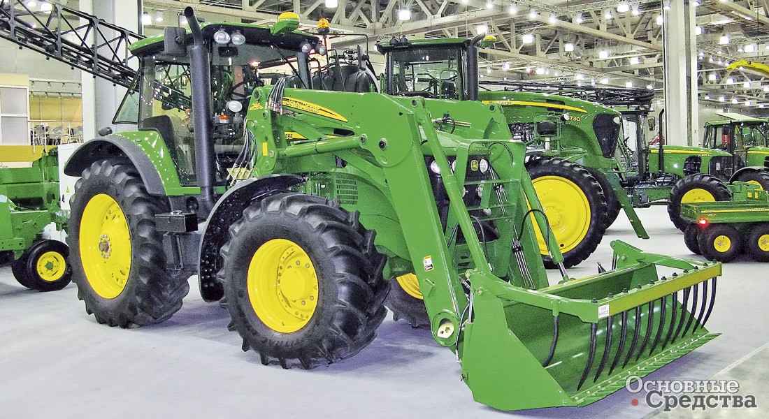 Тракторный погрузчик John Deere с сельскохозяйственным ковшом с вилочным прижимом